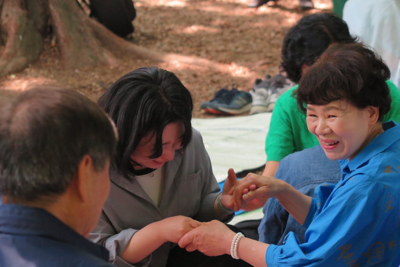 야외예배에서 손을 잡고 함께 기도하며 웃는 성도들
