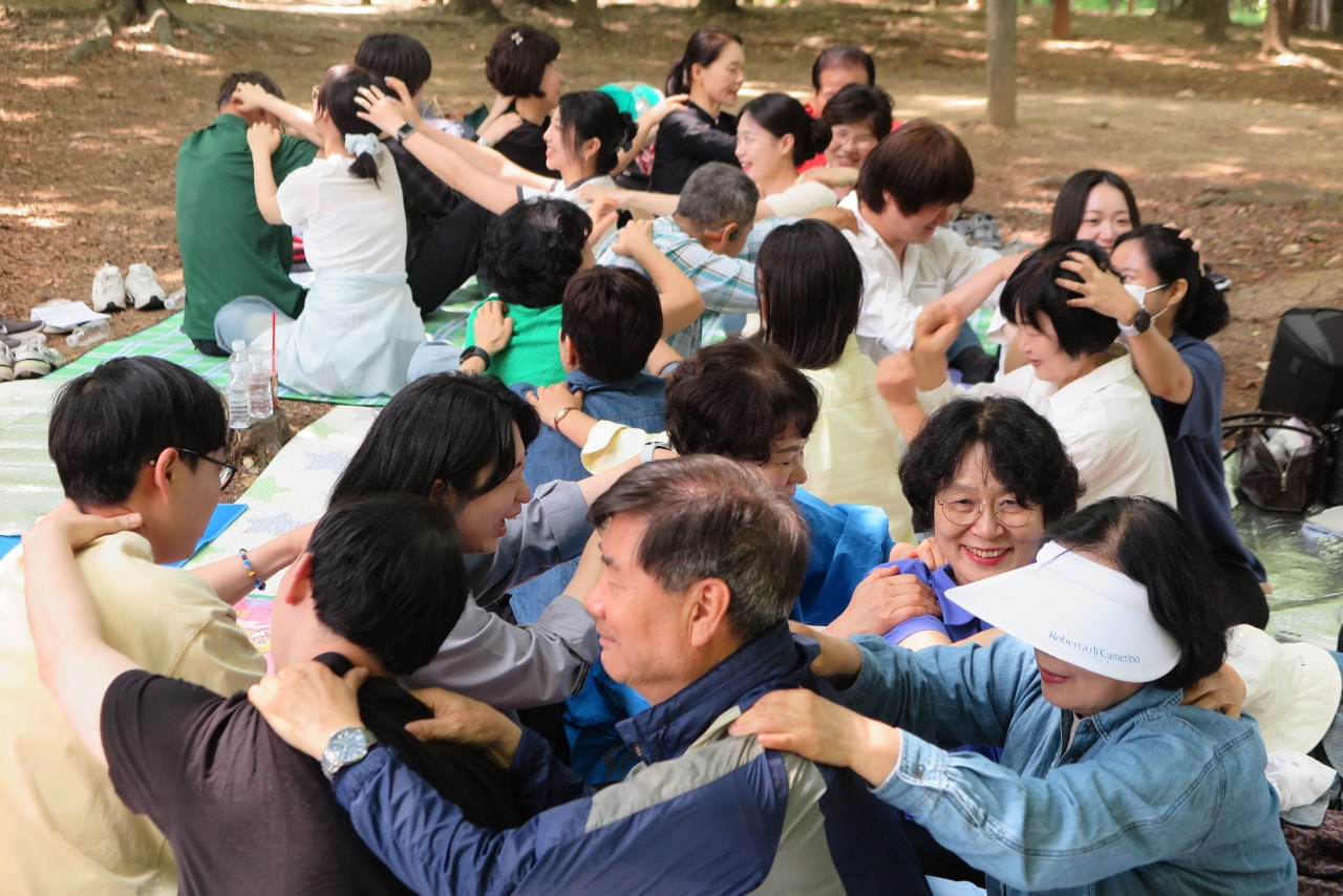 야외예배에서 서로 어깨를 안마해 주며 웃는 제자교회 성도들