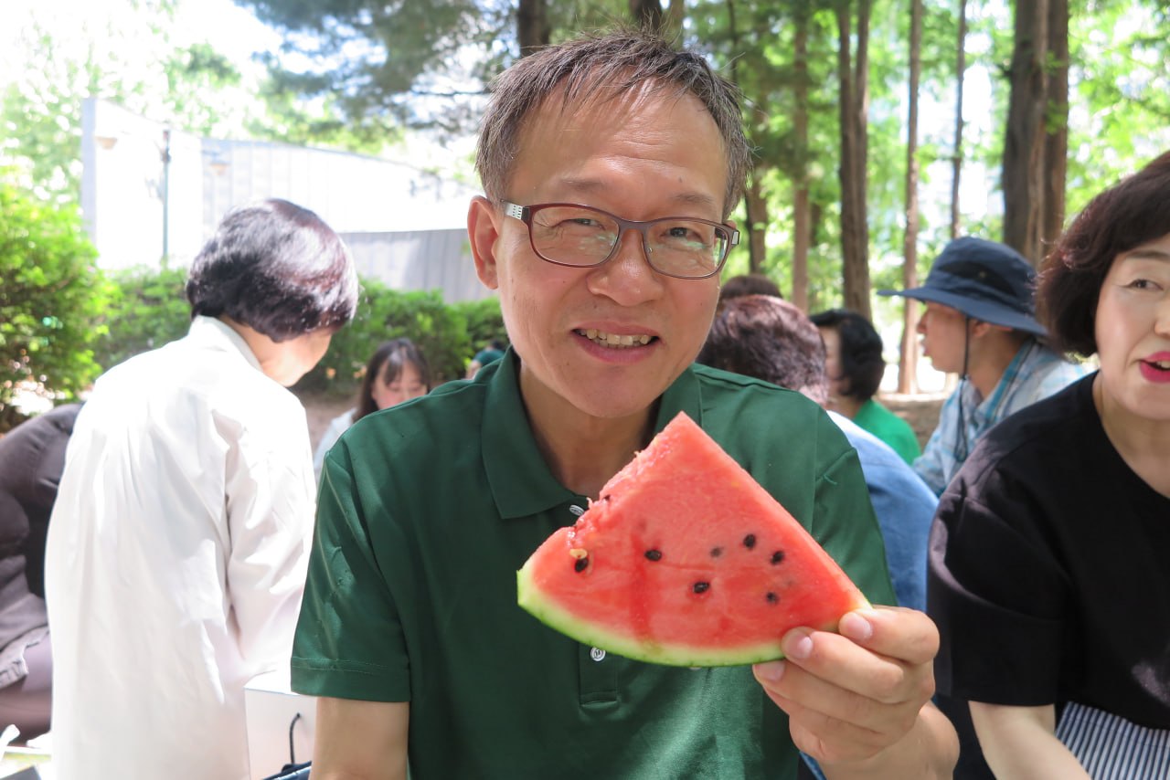 야외예배에서 수박을 나누며 환하게 웃는 장년회장님