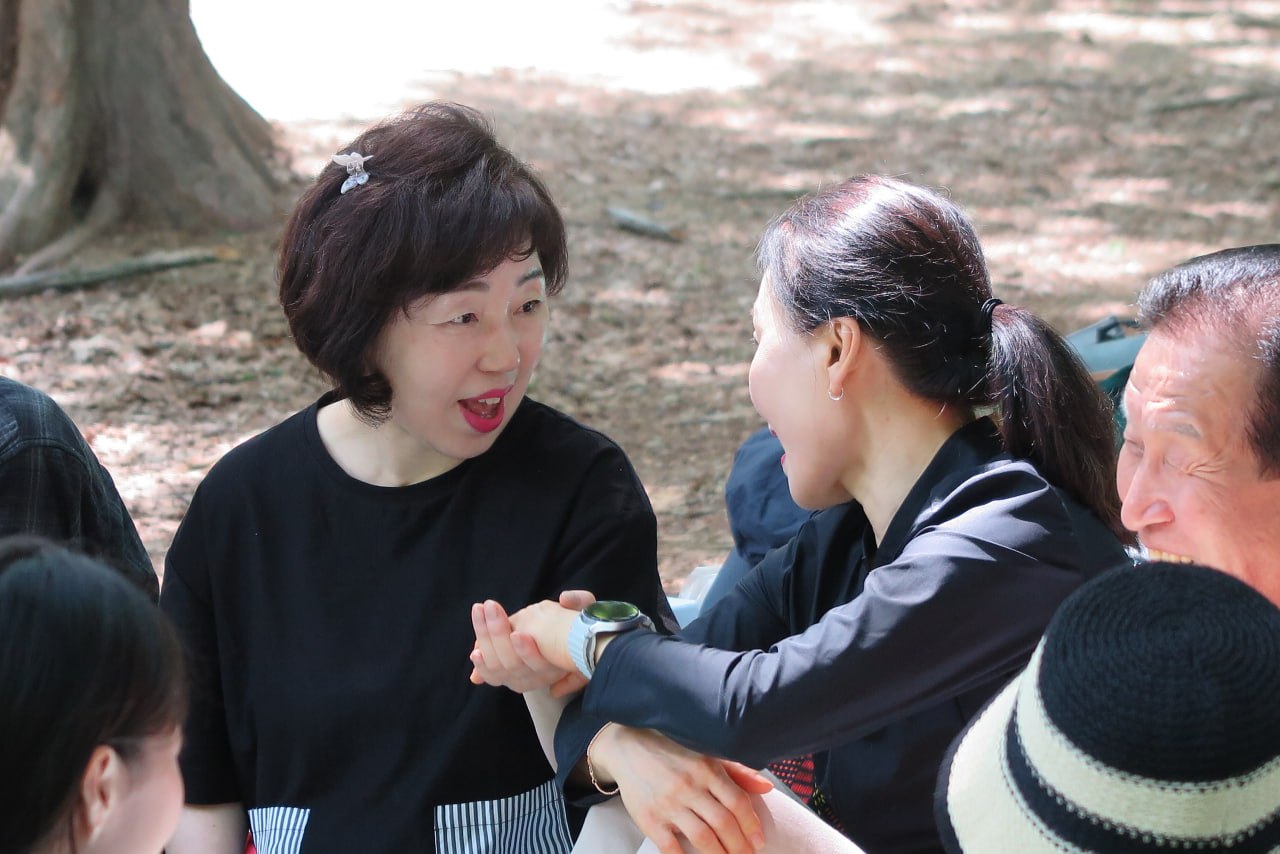 야외예배에서 손을 맞잡고 정겹게 이야기하는 성도들