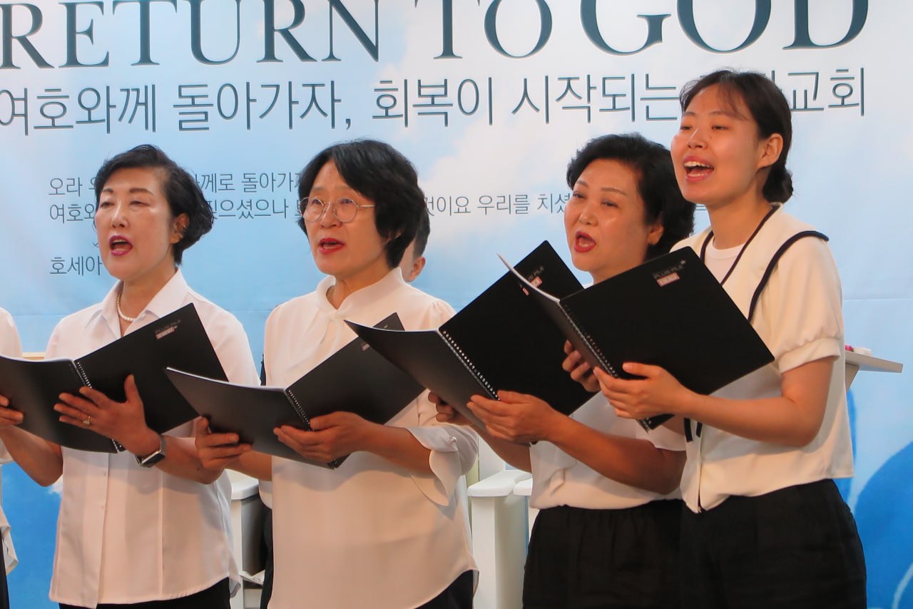 여호와께 돌아가자 배경 앞에서 찬양하는 자매 대원들